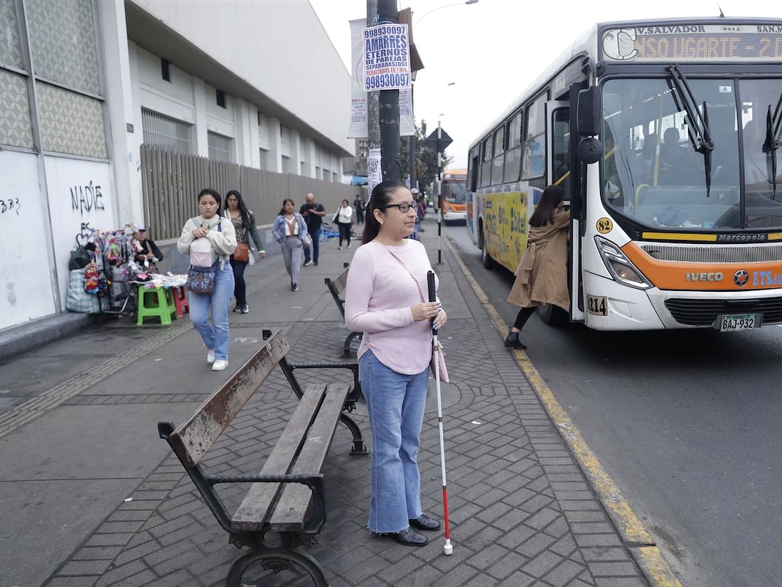 Escena urbana real de las pruebas: una persona con bastón blanco en un paradero junto a un bus, sobre la que se dibujan las detecciones de la inteligencia artificial